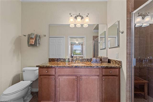 17921 Bonita National Blvd, #244, Bonita Springs, FL 34135 Bathroom vanity featuring a polished stone countertop, wood-finish cabinetry, and an integrated sink with a chrome faucet