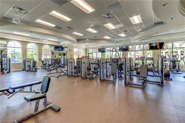 17921 Bonita National Blvd, #244, Bonita Springs, FL 34135 Spacious fitness center featuring a comprehensive array of exercise equipment, high ceilings with recessed lighting, multiple large arched windows, expansive mirror walls, and durable commercial-grade flooring