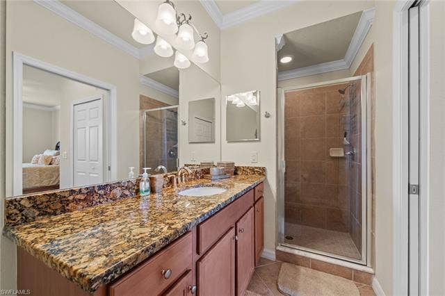 17921 Bonita National Blvd, #244, Bonita Springs, FL 34135 Bathroom with an expansive vanity featuring a stone countertop, an integrated sink with a polished brass-tone faucet, and a large wall-mounted mirror