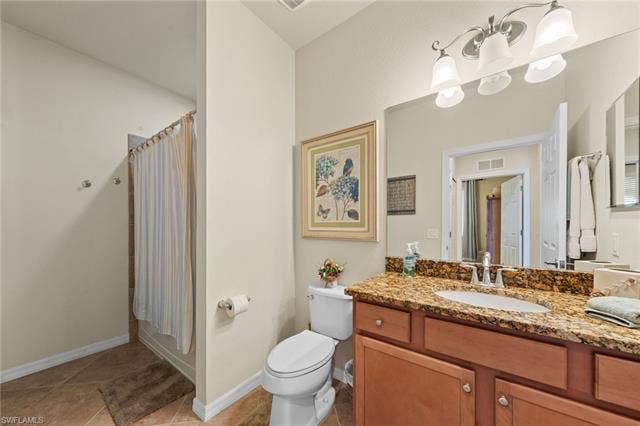 17921 Bonita National Blvd, #244, Bonita Springs, FL 34135 Bathroom featuring a wood-finish vanity with a granite-style countertop, undermount sink, and a multi-bulb vanity light fixture
