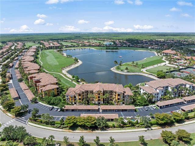 17921 Bonita National Blvd, #244, Bonita Springs, FL 34135 Expansive residential community featuring a large central lake, golf course, multiple multi-story buildings, covered parking structures, and extensive landscaping