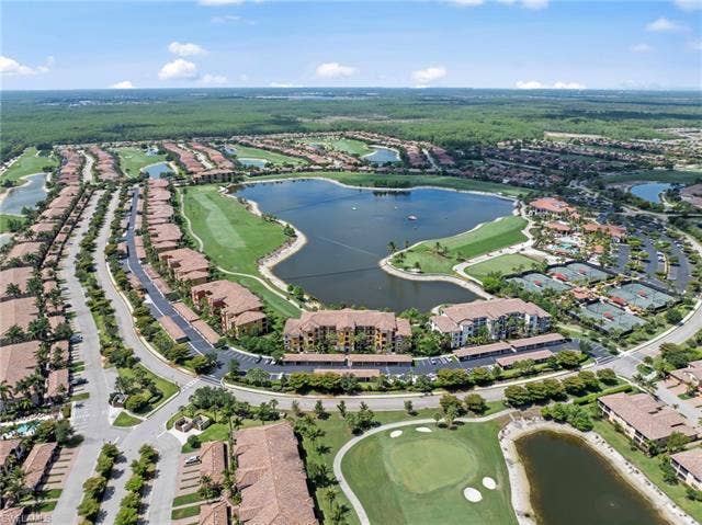 17921 Bonita National Blvd, #244, Bonita Springs, FL 34135 Expansive residential community featuring a central lake, golf course, multiple tennis courts, and numerous multi-story buildings with tile roofs