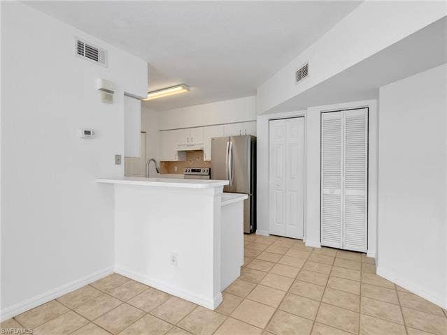 27087 Matheson Ave, #101, Bonita Springs, FL 34135 Kitchen with Tile Flooring, White Cabinetry, Stainless Steel Appliances, Tile Backsplash & Pantry