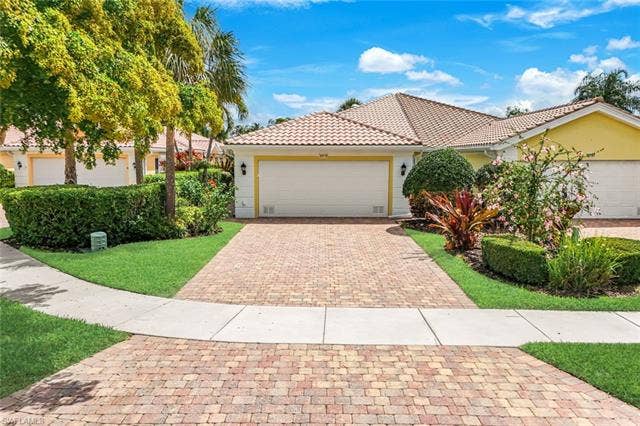 28179 Islet Trl, Bonita Springs, FL 34135 Exterior featuring a two-car garage, concrete tile roof, and a paver driveway