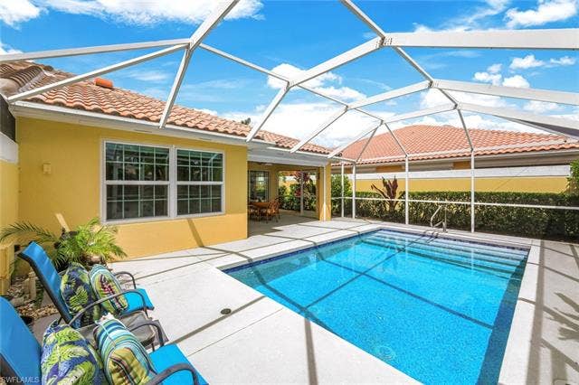28179 Islet Trl, Bonita Springs, FL 34135 Screened-in pool deck featuring a rectangular swimming pool with blue tile interior, a concrete patio, and a covered lanai