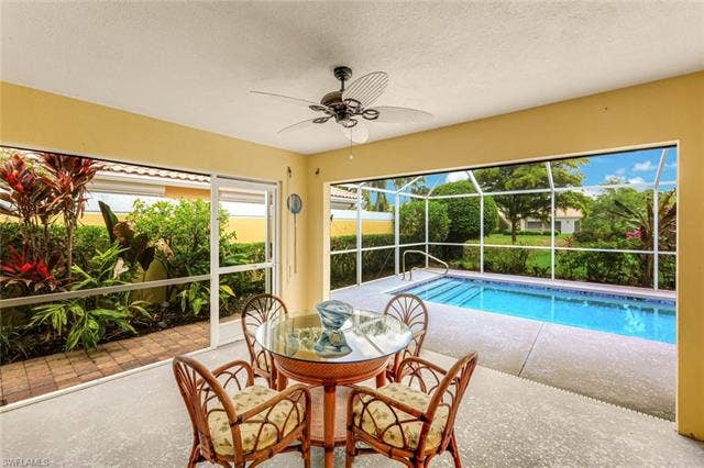 28179 Islet Trl, Bonita Springs, FL 34135 Screened patio featuring an in-ground swimming pool, concrete decking, and lush landscaping