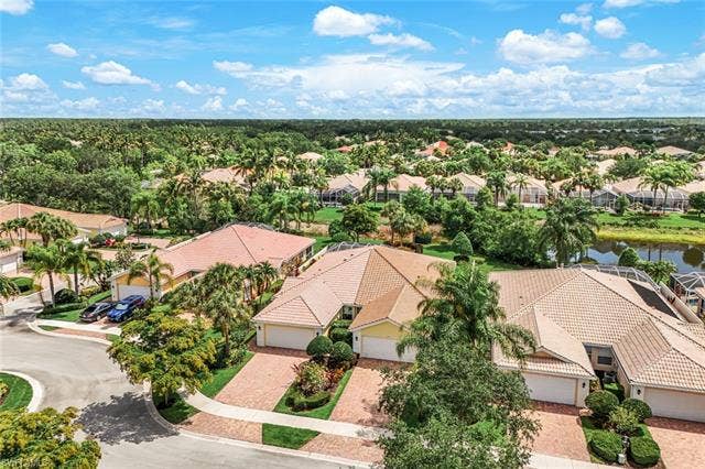 28179 Islet Trl, Bonita Springs, FL 34135 Aerial perspective showcasing a community of homes with tile roofs amidst lush tropical landscaping