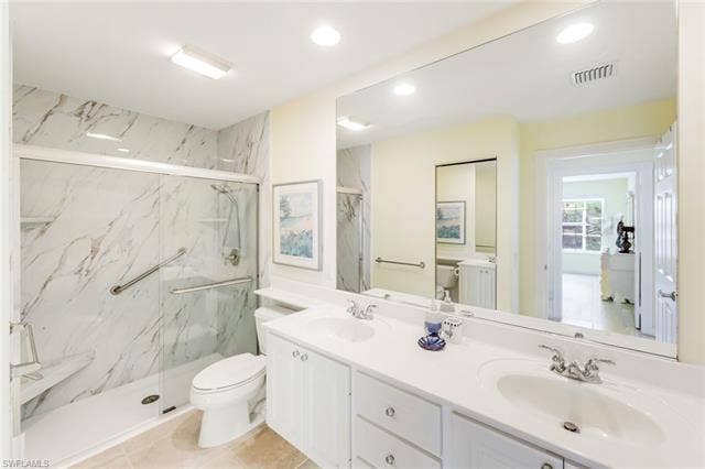 28179 Islet Trl, Bonita Springs, FL 34135 Bathroom featuring a dual vanity with white cabinetry, a spacious mirror, and a shower with sliding glass doors