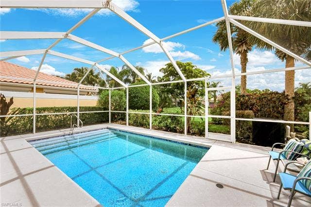 28179 Islet Trl, Bonita Springs, FL 34135 Screened pool enclosure featuring a rectangular pool with integrated steps, a paver pool deck, and lush tropical landscaping