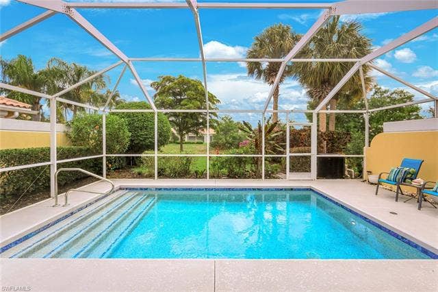 28179 Islet Trl, Bonita Springs, FL 34135 Screened swimming pool enclosure featuring a rectangular pool with tiled steps and a handrail, surrounded by a concrete patio