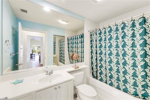 28179 Islet Trl, Bonita Springs, FL 34135 Bathroom featuring a white vanity with integrated sink, chrome faucet, and a wall-mounted mirror