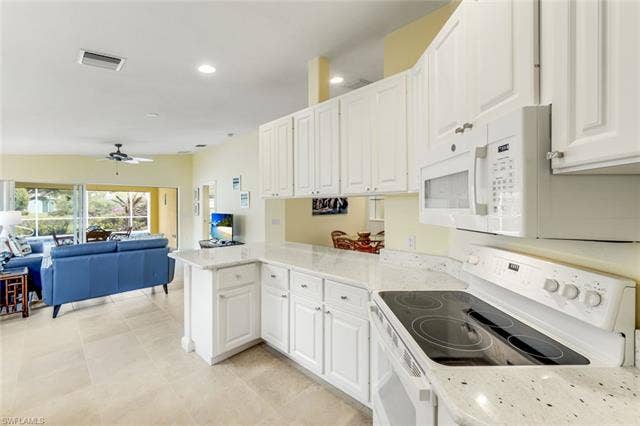 28179 Islet Trl, Bonita Springs, FL 34135 Kitchen featuring white cabinetry, light-colored speckled countertops, and a built-in microwave