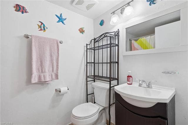 132 Santa Clara Dr, #10, Naples, FL 34104 Bathroom featuring a white vanity with an integrated sink, a chrome-finish faucet, and a wall-mounted mirror