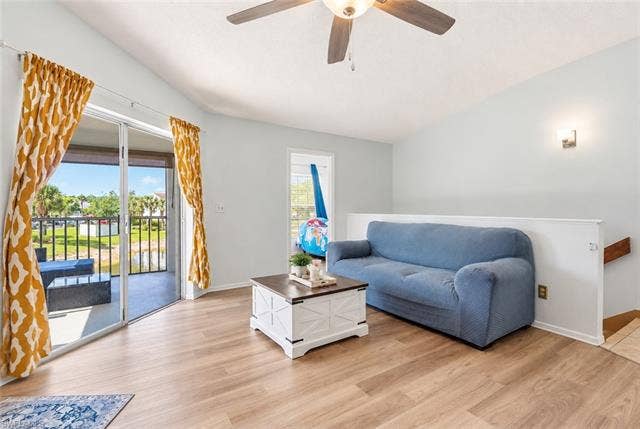 132 Santa Clara Dr, #10, Naples, FL 34104 Vaulted ceiling with a ceiling fan, wood-finish flooring, sliding glass doors to the outdoor balcony, and a partial wall separating spaces