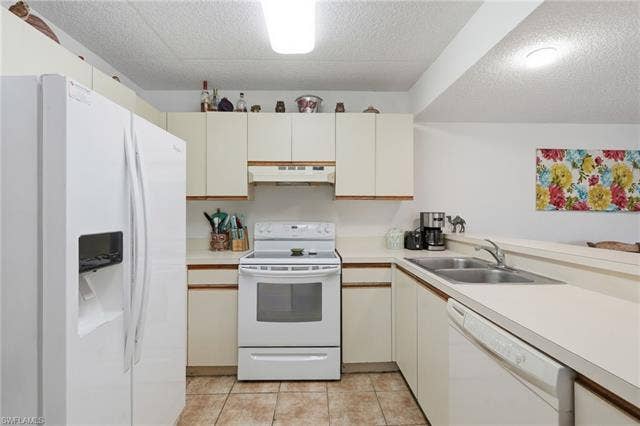 132 Santa Clara Dr, #10, Naples, FL 34104 Kitchen featuring white appliances, cream cabinetry, light-toned countertops, and tile flooring