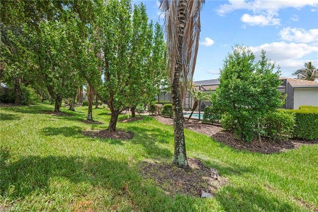 16112 Bonita Landing Cir, Bonita Springs, FL 34135 Grassed area featuring a row of deciduous trees and a palm tree