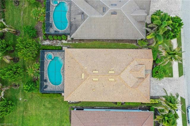 16112 Bonita Landing Cir, Bonita Springs, FL 34135 Aerial perspective showcasing a property with a light brown tile roof, mature landscaping, and an enclosed pool area featuring a kidney-shaped pool and integrated spa