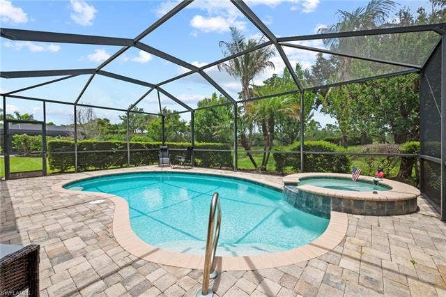 16112 Bonita Landing Cir, Bonita Springs, FL 34135 Screened-in outdoor living space featuring a freeform pool, integrated spa with a waterfall feature, and ample paver decking