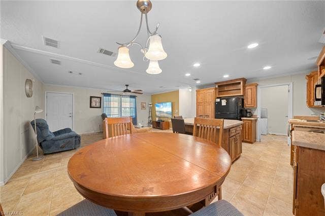 27472 Rue Viauv Ave, Bonita Springs, FL 34135 Open-concept living space with tile flooring, a dining area featuring a pendant light fixture, a kitchen island with storage, wood cabinetry, and a ceiling fan in the living room area