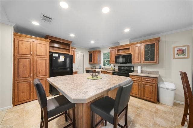 27472 Rue Viauv Ave, Bonita Springs, FL 34135 Kitchen featuring wood cabinetry, a central island with seating, black appliances, recessed lighting, and tile flooring