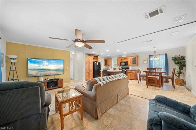 27472 Rue Viauv Ave, Bonita Springs, FL 34135 Open-concept interior featuring tile flooring, a living area with a ceiling fan, a kitchen with wood cabinetry and black appliances, and a dining area with a chandelier