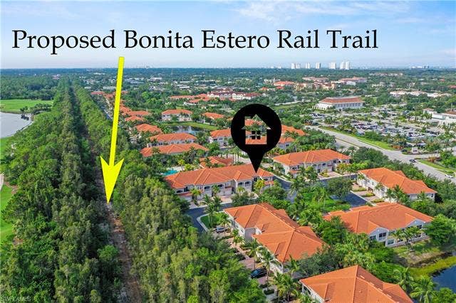 23461 Alamanda Dr, #206, Estero, FL 34135 Aerial perspective showcasing a residential community with red-tiled roofs, mature landscaping, and water features