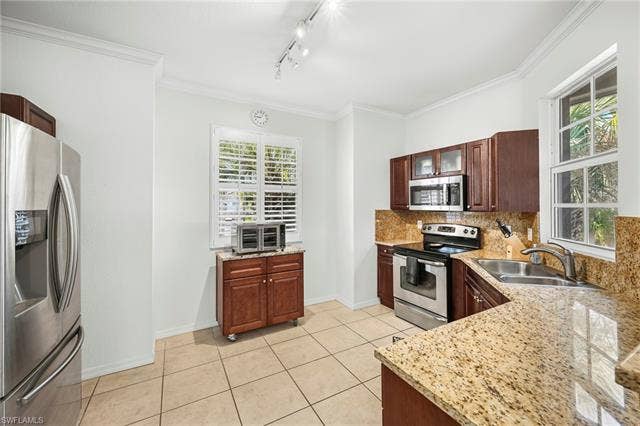 23461 Alamanda Dr, #206, Estero, FL 34135 Kitchen featuring granite countertops, stainless steel appliances, dark wood cabinetry, tile flooring, and track lighting