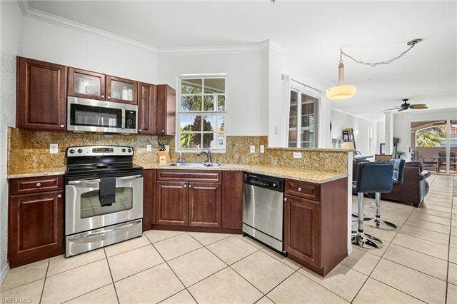 23461 Alamanda Dr, #206, Estero, FL 34135 Kitchen featuring wood cabinetry, stainless steel appliances, speckled stone countertops, and a tile backsplash