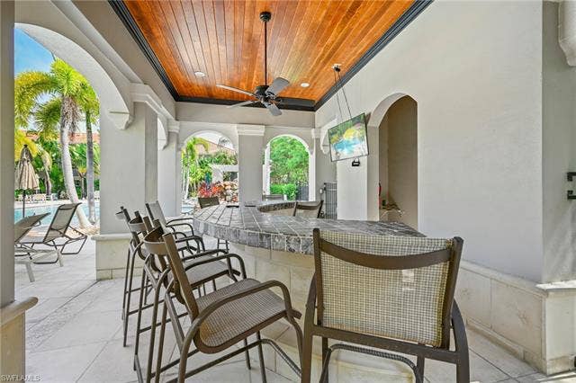 23461 Alamanda Dr, #206, Estero, FL 34135 Outdoor bar area featuring a tiled countertop, wood-finish ceiling, and arched architectural details