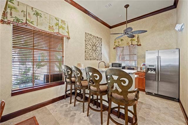 23461 Alamanda Dr, #206, Estero, FL 34135 Kitchenette featuring a built-in island with seating, stainless steel refrigerator, integrated sink, and ceiling fan