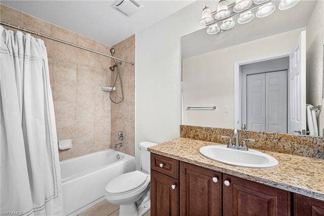 23461 Alamanda Dr, #206, Estero, FL 34135 Full bathroom featuring a rich wood-finish vanity with a granite countertop and an undermount sink