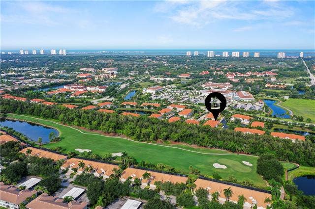 23461 Alamanda Dr, #206, Estero, FL 34135 Expansive aerial showcasing a golf course property with verdant fairways, multiple water features, and surrounding residential structures