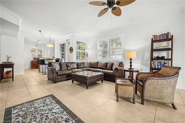 23461 Alamanda Dr, #206, Estero, FL 34135 Spacious living area featuring large format tile flooring, crown molding, and plantation shutters