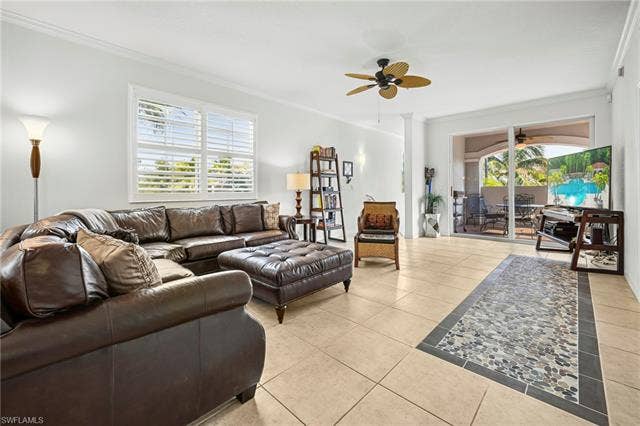 23461 Alamanda Dr, #206, Estero, FL 34135 Light-filled living area featuring neutral tile flooring with a decorative pebble inlay, crown molding, and a ceiling fan