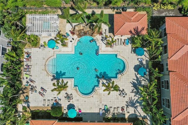 23461 Alamanda Dr, #206, Estero, FL 34135 Expansive, clover-shaped pool featuring integrated steps and a rock waterfall feature