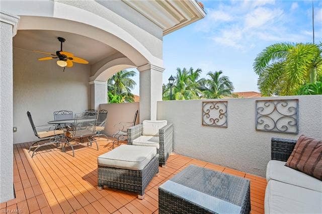 23461 Alamanda Dr, #206, Estero, FL 34135 Covered patio featuring wood-finish flooring, an arched entryway, and a ceiling fan with integrated lighting