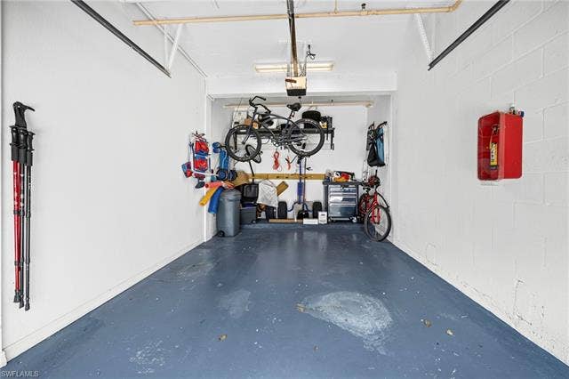 23461 Alamanda Dr, #206, Estero, FL 34135 Spacious garage featuring white-painted cinder block walls and a blue-painted concrete floor