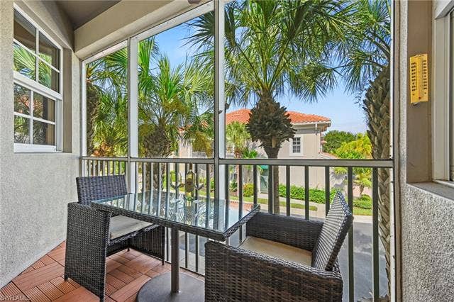 23461 Alamanda Dr, #206, Estero, FL 34135 Screened balcony featuring wood-finish floor tiles and a window with grid patterns