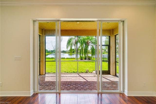 10310 Carolina Willow Dr, Fort Myers, FL 33913 Hardwood-finish flooring, crown molding, sliding glass doors, screened patio with brick paver flooring, and water feature