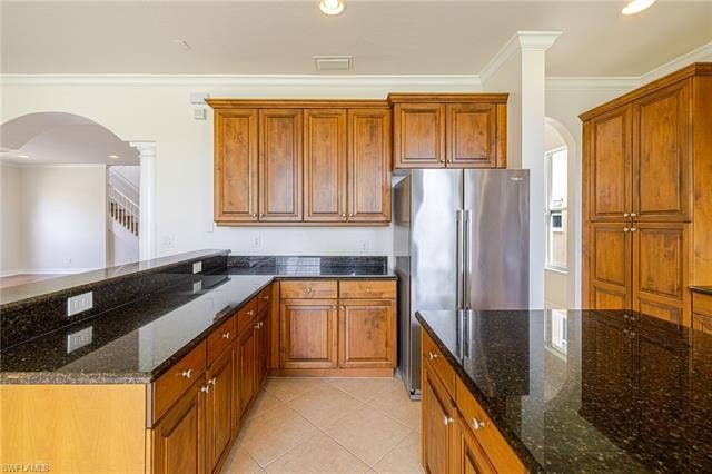10310 Carolina Willow Dr, Fort Myers, FL 33913 Kitchen featuring wood cabinetry, stainless steel refrigerator, dark granite countertops, tile flooring, and crown molding