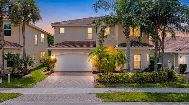10310 Carolina Willow Dr, Fort Myers, FL 33913 Stucco exterior with a tiled roof, paver driveway, and an arched garage door