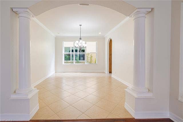10310 Carolina Willow Dr, Fort Myers, FL 33913 Arched entryway with decorative columns, tile flooring, crown molding, and a chandelier-style light fixture