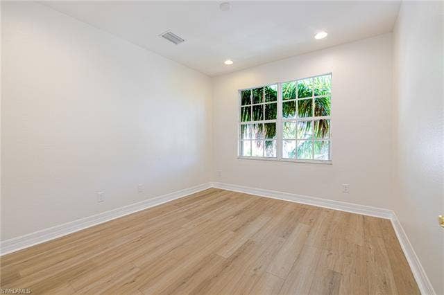 10310 Carolina Willow Dr, Fort Myers, FL 33913 Bright and airy bedroom showcasing wood-finish flooring, recessed ceiling lighting, and a large multi-pane window framed with white trim that floods the space with natural light