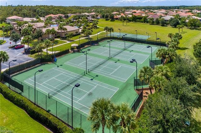 10310 Carolina Willow Dr, Fort Myers, FL 33913 Multiple hard surface tennis courts with perimeter fencing, surrounded by manicured landscaping and mature palm trees