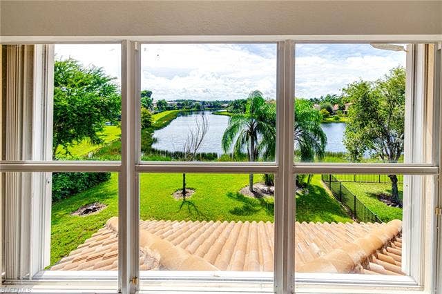 10310 Carolina Willow Dr, Fort Myers, FL 33913 Window featuring a lake, expansive green space, mature trees, and a terracotta tile roof