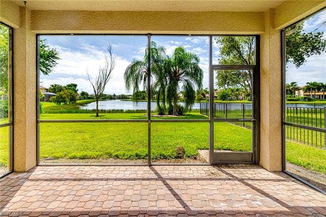 10310 Carolina Willow Dr, Fort Myers, FL 33913 Screened patio with paver flooring, providing direct access to a grassy expanse and a tranquil water feature