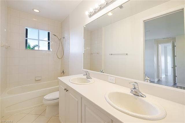 10310 Carolina Willow Dr, Fort Myers, FL 33913 Dual vanity with white cabinetry, integrated sink basins, chrome fixtures, and a large wall-mounted mirror