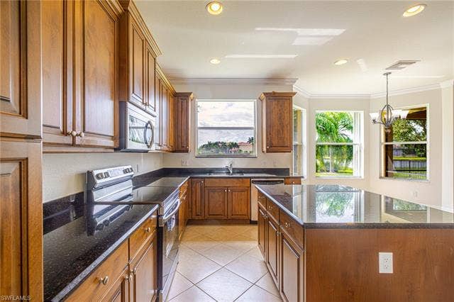 10310 Carolina Willow Dr, Fort Myers, FL 33913 Kitchen featuring wood cabinetry, dark countertops, a central island, recessed lighting, and tile flooring