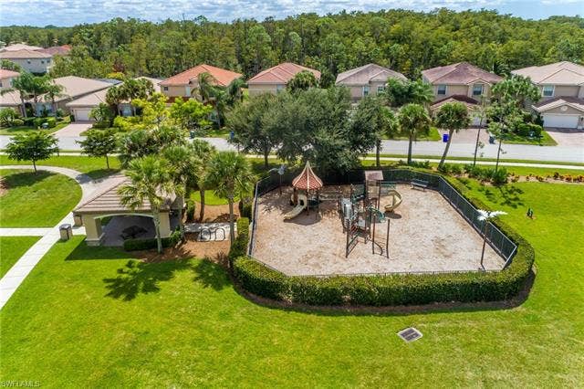 10310 Carolina Willow Dr, Fort Myers, FL 33913 Expansive backyard oasis featuring a custom playground structure with multiple levels, surrounded by mature landscaping and lush lawn