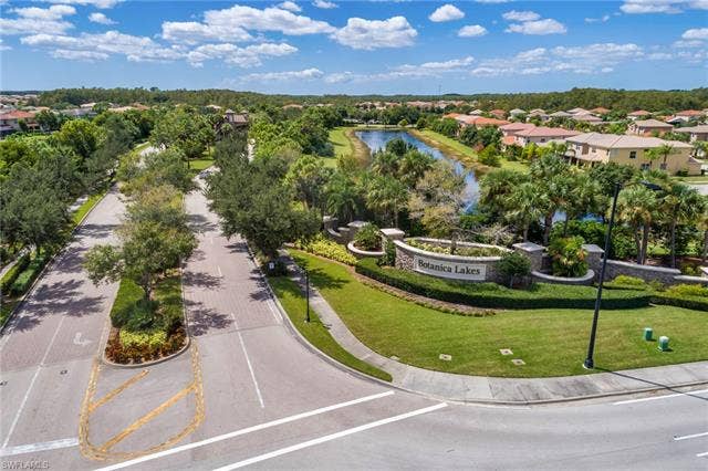 10310 Carolina Willow Dr, Fort Myers, FL 33913 Botanica Lakes entrance featuring stone signage, manicured landscaping, and mature trees